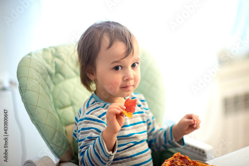 A child eats pizza. Fast food for children. Italian cuisine. Baby food. Delicious food for the child  selective focus