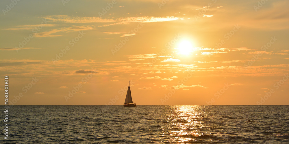 Panoramic photo of sailing boat sails on the sea at sunset. Copy space for text.