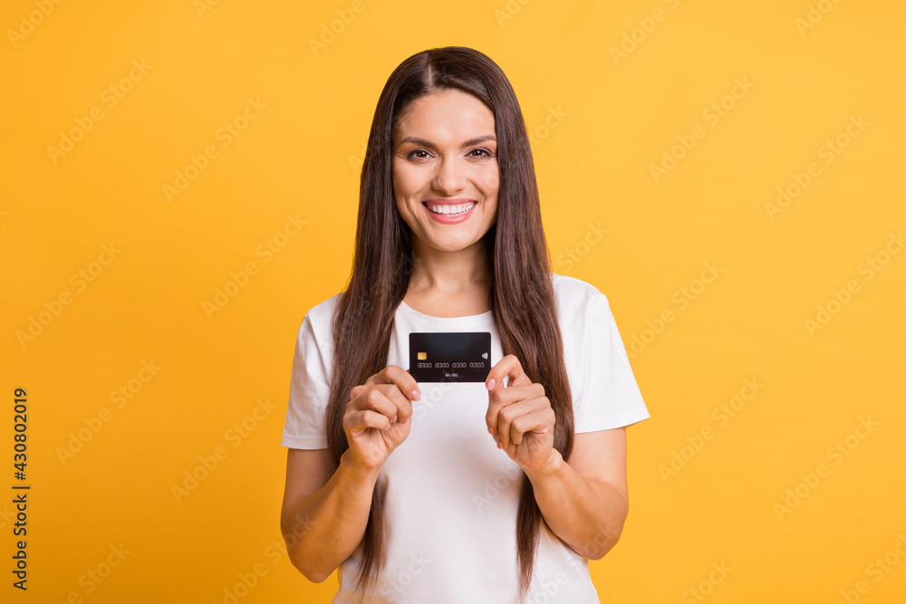 Naklejka premium Photo portrait of happy business woman showing plastic bank wearing casual clothes isolated on vivid yellow color background