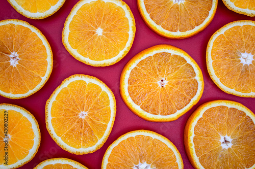 Yellow juicy orange on a red background. Background on the theme of fruits  citrus fruits.