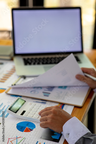 Close up Business man using calculator and laptop for do math finance on wooden desk  tax  accounting  statistics and analytical research concept