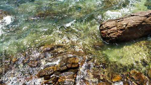 Scenic aerial view of sea water flowing through the rocks while hitting the stones. © Chamika