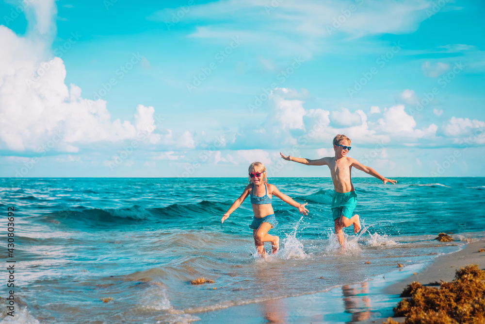 little girl and boy run and play with water at beach