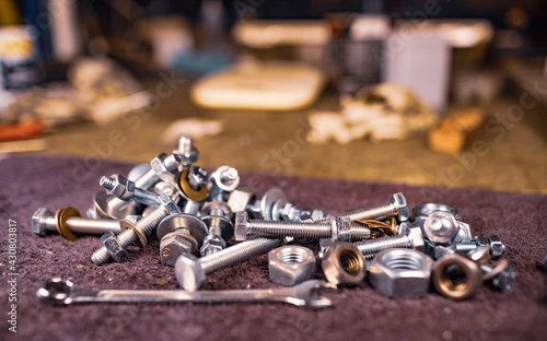 Metal nuts bolts and a wrench lie on the work table of the assembler