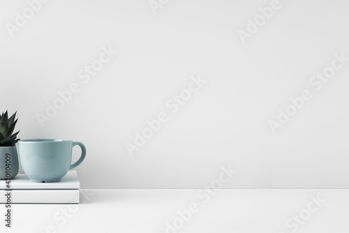 The mug stands on a stack of books on a white background. Natural and eco-friendly materials. Copy space, mock up.