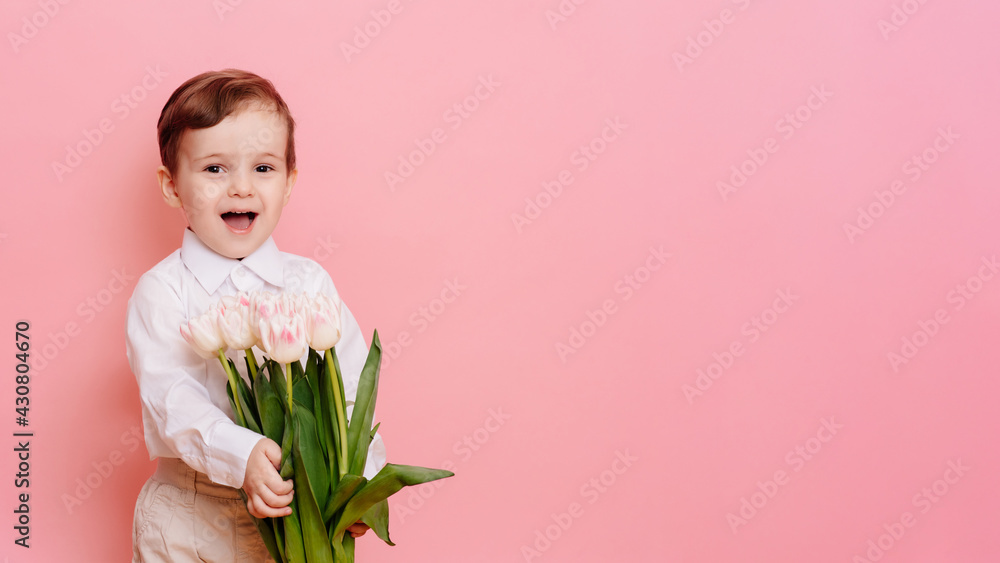 A happy boy gentleman holds a bouquet of delicate pink tulips in his hands. Space for your text, copy space A happy boy gentleman holds a bouquet of delicate pink tulips in his hands. Space for your text, copy space