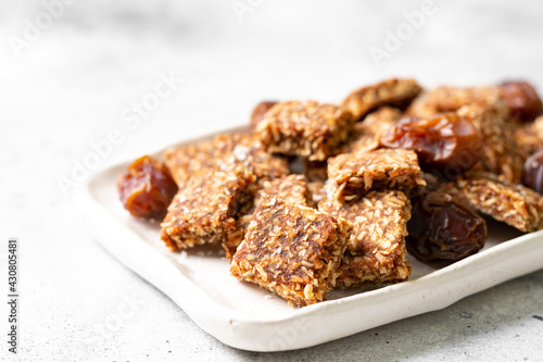 Coconut cookies with dates and carrots in a white bowl on a light background close-up. The concept of a healthy snack no sugar