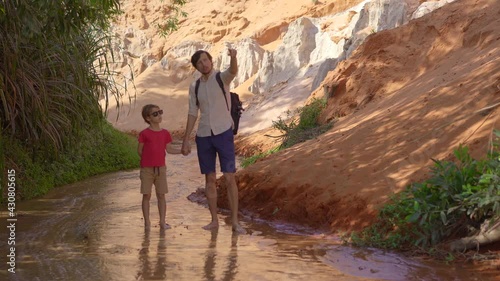 A family walks along a red canyon or Fairy stream at the border of desert in the Mui Ne village in southern Vietnam photo