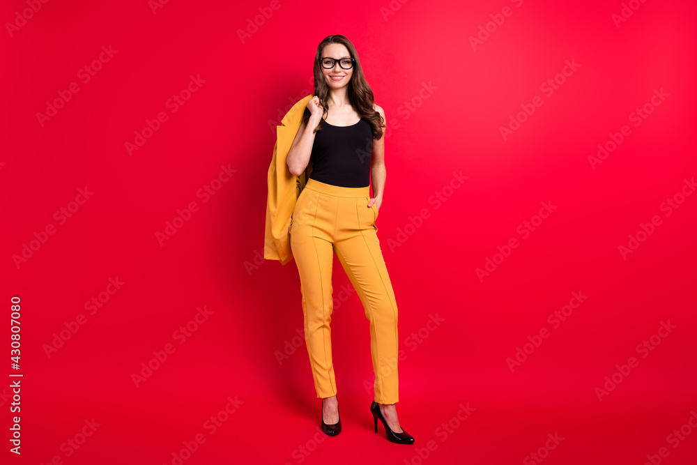 Full length body size view of attractive cheerful chic girl posing holding blazer isolated over bright red color background Full length body size view of attractive cheerful chic girl posing holding blazer isolated over bright red color background