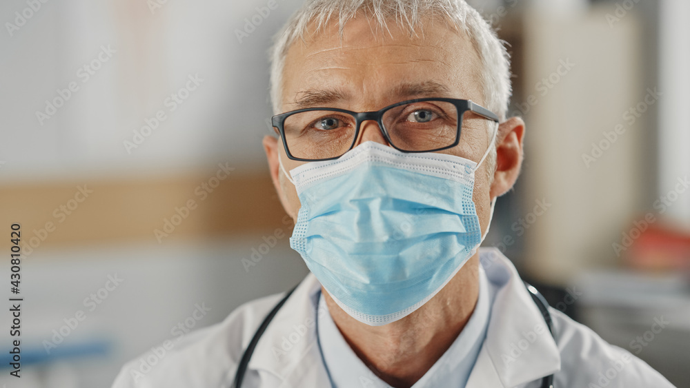 Close Up Portrait of a Senior Caucasian Male Doctor or Surgeon Wearing a Protective Face Mask and Glasses. Middle Aged Scientist Calmly Looking at Camera. Medical Care Specialist in Covid-19 Reality. Close Up Portrait of a Senior Caucasian Male Doctor or Surgeon Wearing a Protective Face Mask and Glasses. Middle Aged Scientist Calmly Looking at Camera. Medical Care Specialist in Covid-19 Reality.