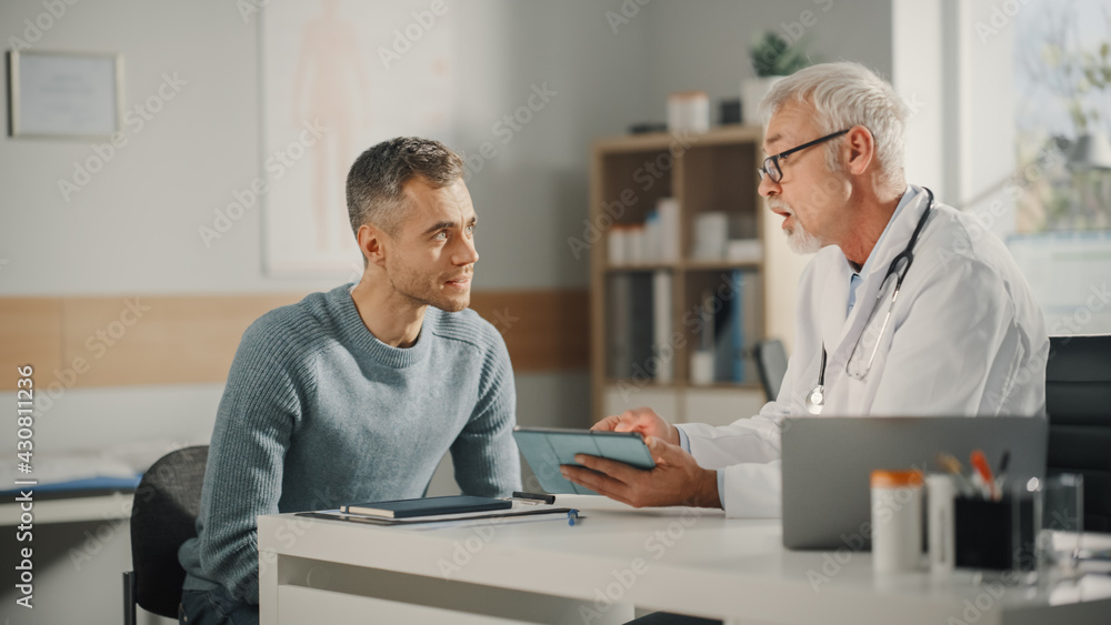 Obraz premium Experienced Middle Aged Family Doctor Showing Analysis Results on Tablet Computer to Male Patient During Consultation in a Health Clinic. Physician Sitting Behind a Desk in Hospital Office.