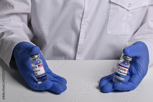 Doctor shows American and Russian Covid vaccine phials. Drugstore man offers inoculation against Covid-19 virus. Vaccine remedy made in USA and Russia. How to select Covid vaccination treatment.