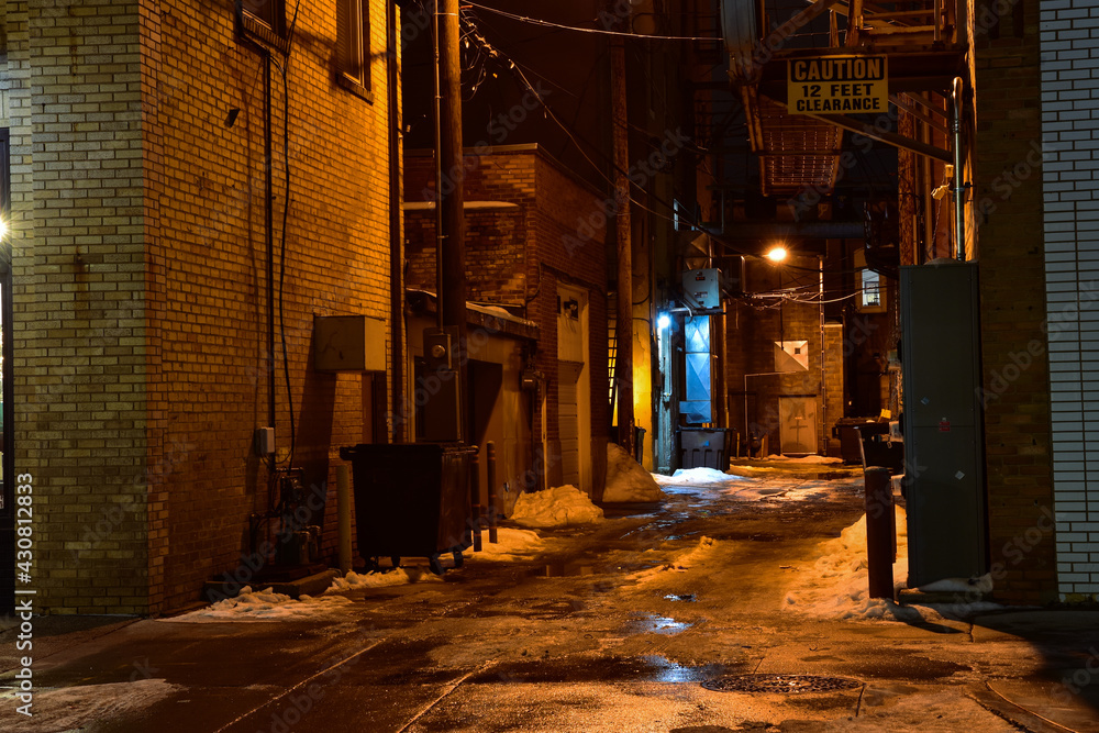Dimly lit downtown alley after dark .