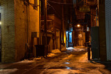 Dimly lit downtown alley after dark .