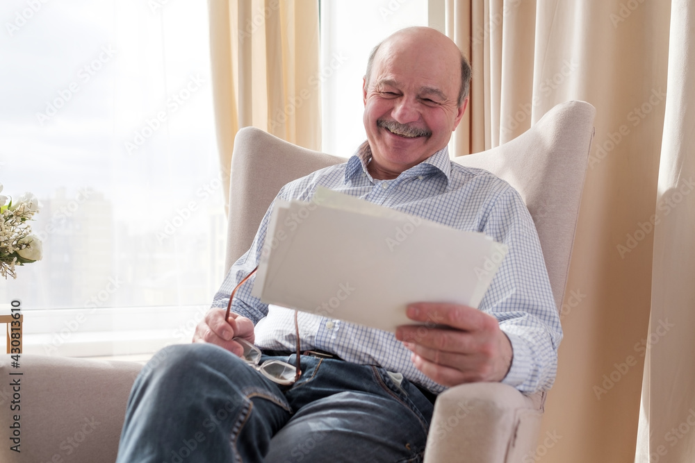Senior man wathcing photos of his family smiling Senior man wathcing photos of his family smiling
