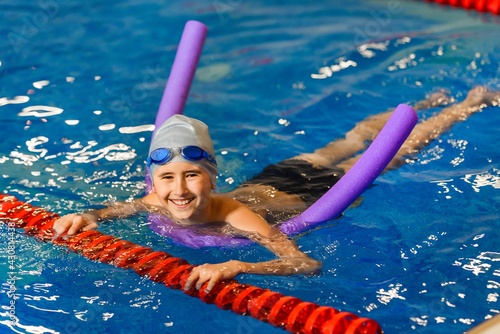 Obraz na plátně The boy in the pool learns to swim using a stick of foam