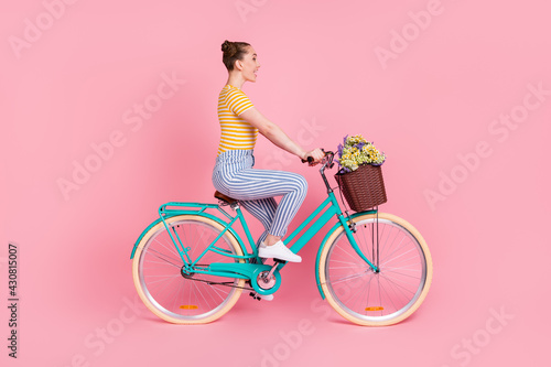 Full size profile photo of optimistic nice brunette ride bicycle wear t-shirt pants isolated on pink background