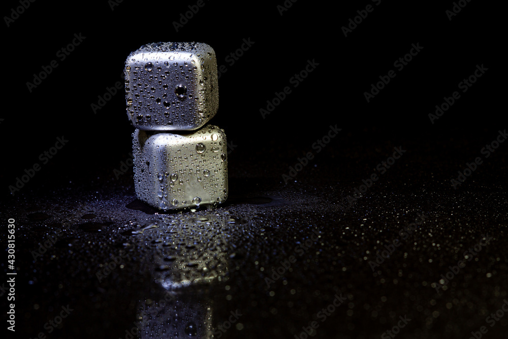 Stainless steel cubes simulating ice for cooling drinks on a black surface with a reflection. Stainless steel cubes simulating ice for cooling drinks on a black surface with a reflection.