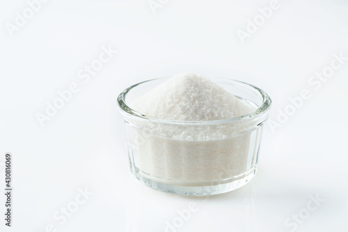 White sugar in glass bowl isolated on white background. Selective focus.