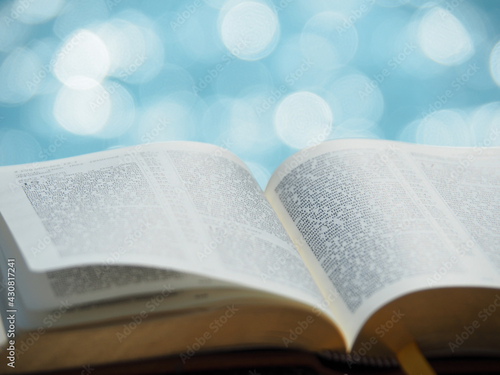 Obraz premium Open bible on sunlight with blue sea bokeh. Christianity, study bible, God word concept.