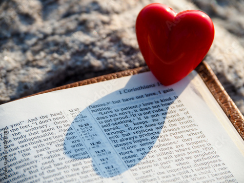 Open bible page 1 Corinthians 13:4 Love is patient. And red heart on stone. God is love , Christianity, study bible, God word, Wedding ceremony Concept.

