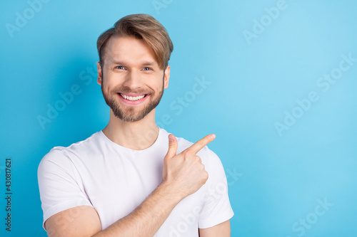 Photo of satisfied man toothy smile indicate finger empty space proposition isolated on blue color background