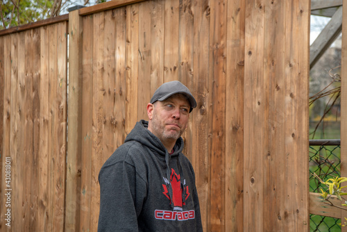 A white, middle-aged gay man builds a wooden fence in his back yard. © Robert