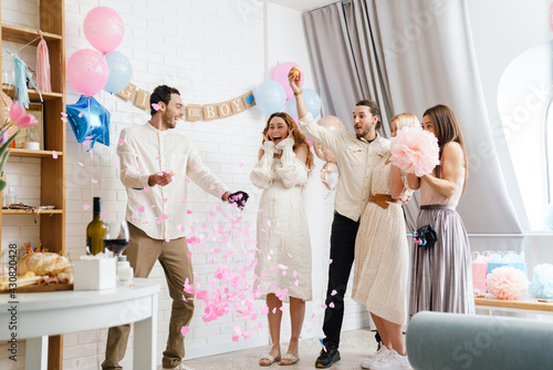 Картината върху платно Excited couple blowing up surprise balloon during gender reveal party