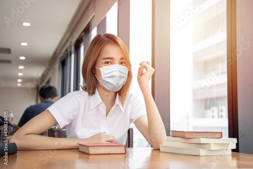 Asian Thai university girl teen waring face mask for healthy prevent Corona virus(COVID-19) in library public space.