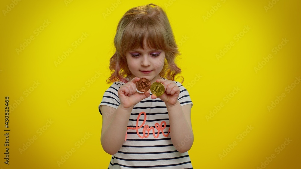 Portrait of funny blonde child girl 5-6 years old showing golden bitcoins. Achievement career wealth, cryptocurrency investment, mining, future technology. Teen kid children on yellow wall background Portrait of funny blonde child girl 5-6 years old showing golden bitcoins. Achievement career wealth, cryptocurrency investment, mining, future technology. Teen kid children on yellow wall background