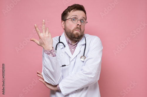 Принти на полотні Young Caucasian doctor makes a hand gesture in bewilderment and looks in surprise