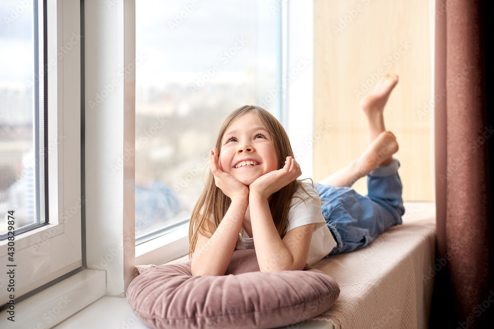 cheerful smiling girl lies and dream on comfortable windowsill on vacation cheerful smiling girl lies and dream on comfortable windowsill on vacation