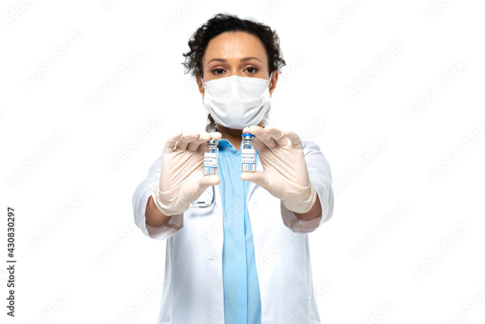 Jars with vaccine in hands of african american doctor in medical mask on blurred background isolated on white