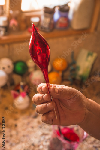 Craftsman painting Christmas spheres in his workshop in different colors, using acrylic paint, diamond paint to give texture and different figures. © Marco