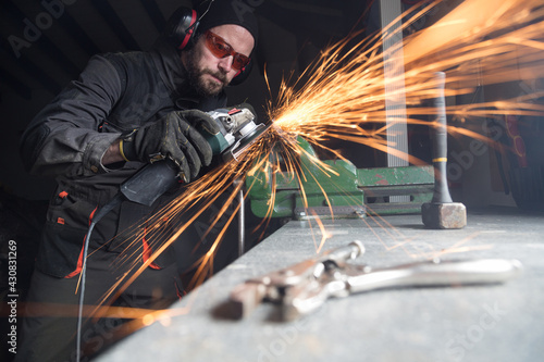 Worker using metal grinder in workshop creating sparks