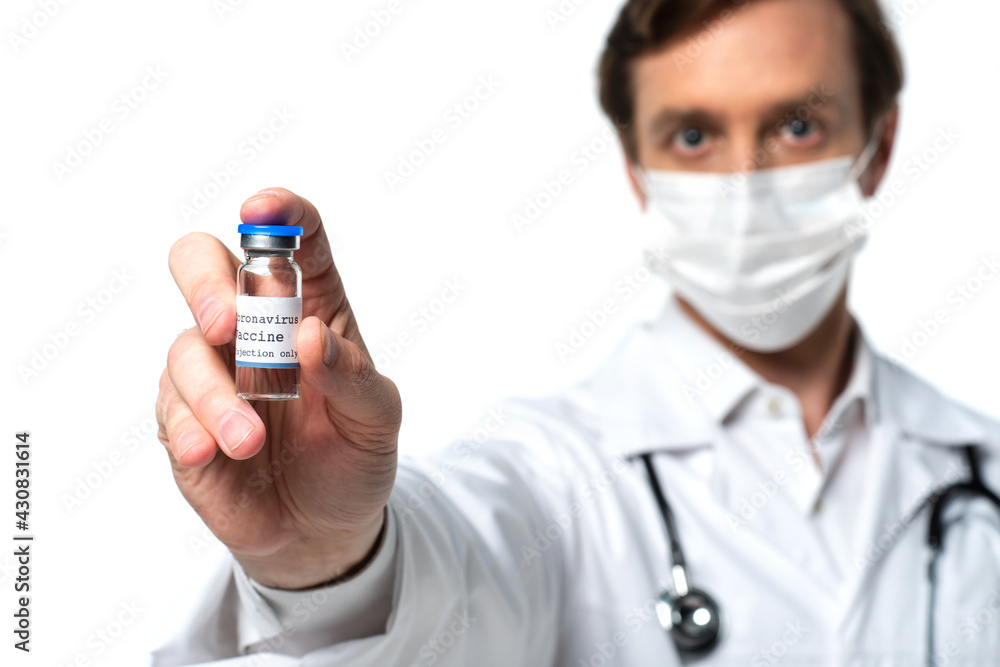 Vaccine in hand of doctor in medical mask on blurred background isolated on white Vaccine in hand of doctor in medical mask on blurred background isolated on white