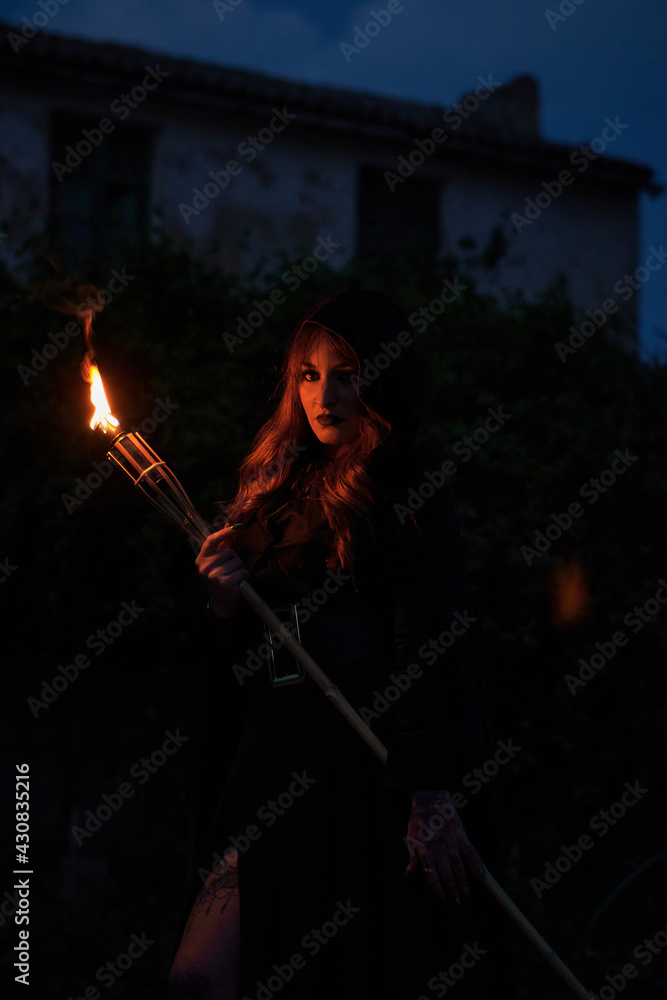 Woman disguised as a witch holding a flaming torch