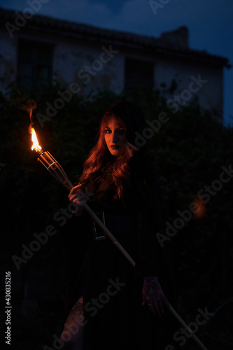 Woman disguised as a witch holding a flaming torch © Cristian Blázquez