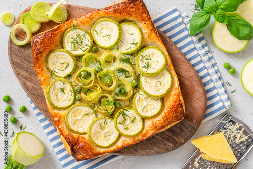 Vegetarian vegetable pie. Tasty summer pie with zucchini, leek and peas on a light background top view.
