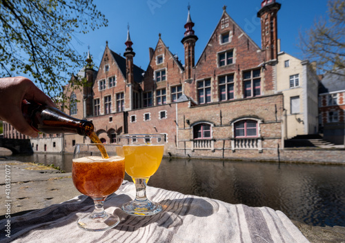 Tasting of Belgian beer on open cafe or bistro terrace with view on medieval houses and canals in Bruges, Belgium
