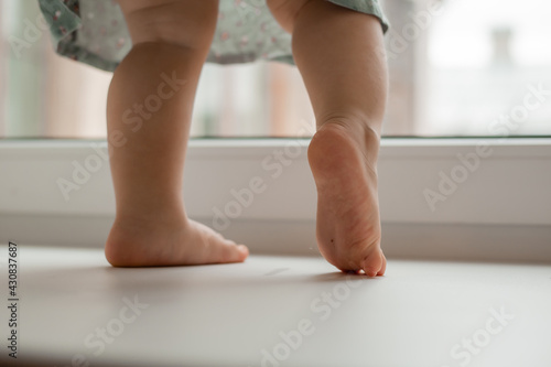 child's feet on the windowsill of the house near the window close-up