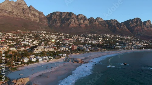 Panning aerial shot showing Camps Bay Beach, Twelve Apostoles and Lions Head at sunset in Cape Town, Western Cape, South Africa.  photo