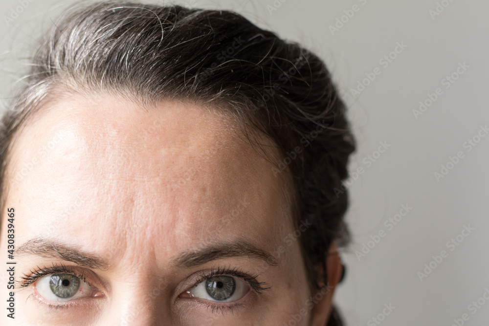 Forty year old woman gazing at camera; natural gray hair growing in Forty year old woman gazing at camera; natural gray hair growing in