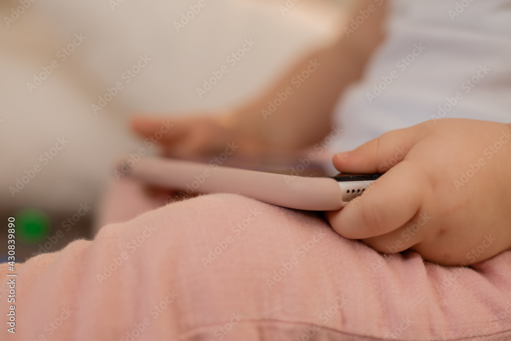 Baby blonde girl plays with the phone at home on the bed. Children and technology Baby blonde girl plays with the phone at home on the bed. Children and technology
