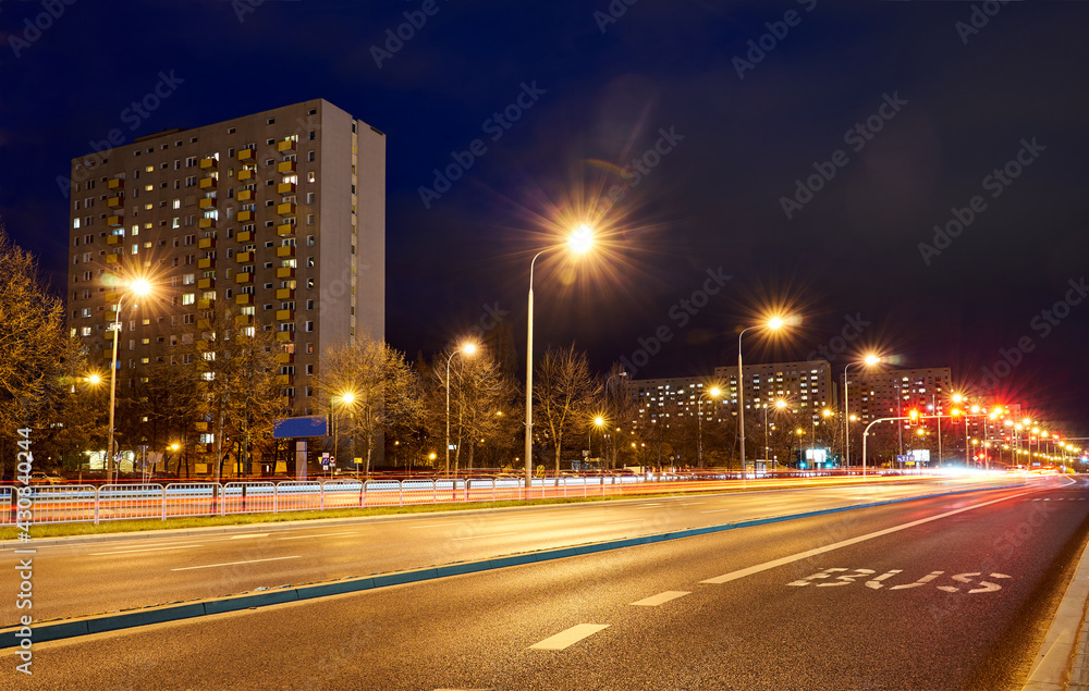 Multi-story residential buildings and a street with cars at night