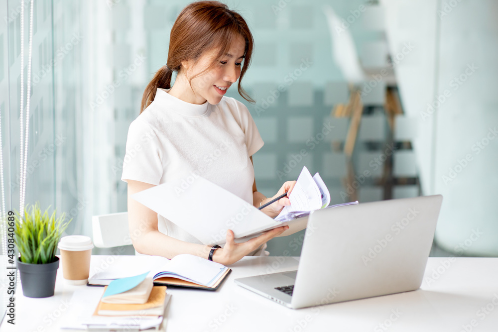 Image of young pleased happy cheerful cute beautiful business woman sit indoors in office using laptop computer,analyzing real estate investment data, Financial and tax systems concept. Image of young pleased happy cheerful cute beautiful business woman sit indoors in office using laptop computer,analyzing real estate investment data, Financial and tax systems concept.