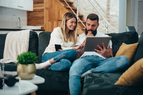 Photography Young attractive couple using a smartphone and a digital tablet while surfing th