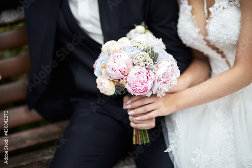 Bride holding a wedding bouquet in the hands standing near groom