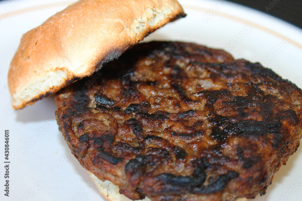 Close-up of a plain, undressed hamburger on a toasted hamburger bun. Close-up of a plain, undressed hamburger on a toasted hamburger bun.
