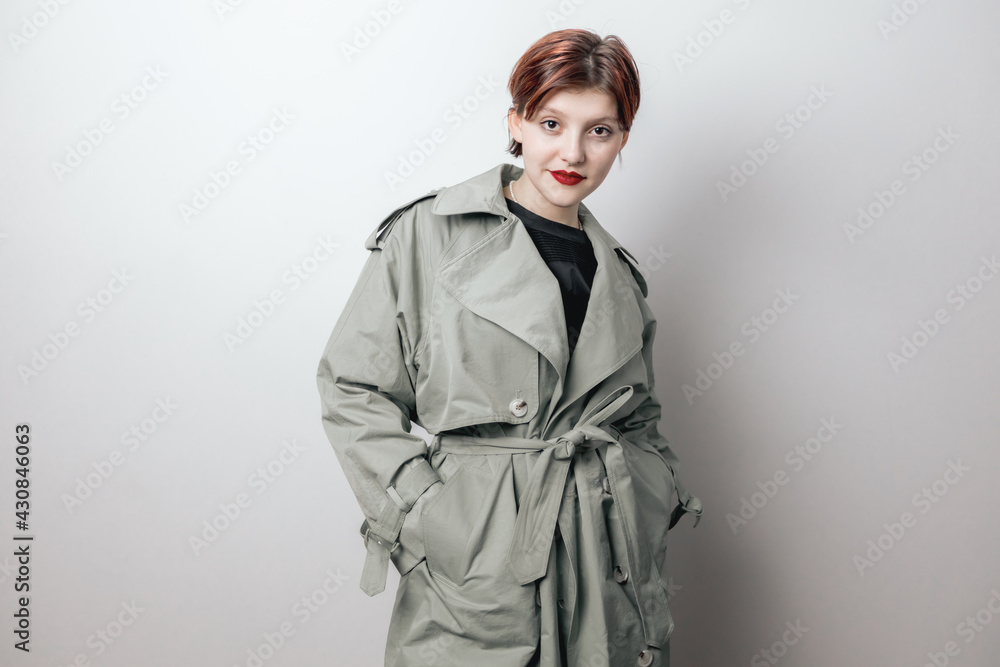 A fashionable girl poses in a spring coat. White background